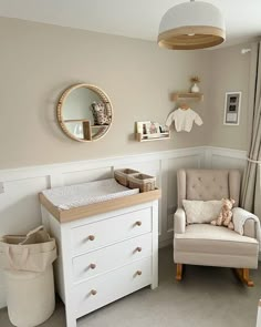 a baby's room with a chair, dresser and mirror