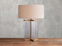 a lamp that is on top of a wooden table with a beige shade over it