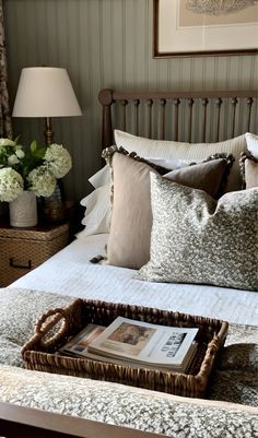 a bed with pillows and pictures on the headboard, along with a basket full of flowers