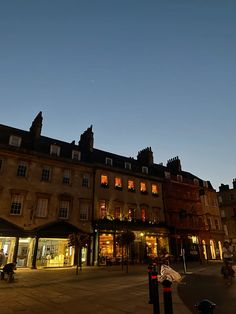 an old building is lit up at night in the town square with people walking around