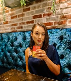 a woman sitting at a table with a drink in her hand