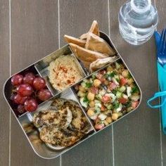 a metal tray filled with different types of food next to a fork and glass of water