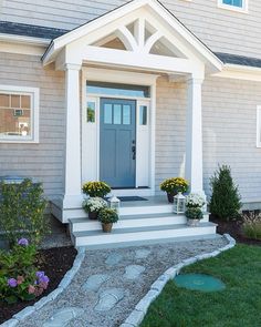 a front porch with steps leading up to the door and flowers in pots on either side