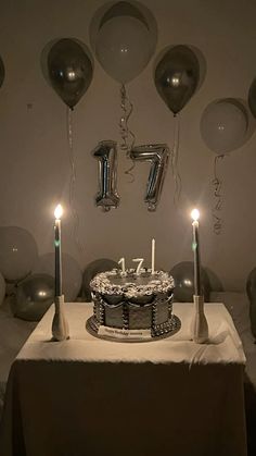 a birthday cake sitting on top of a table surrounded by balloons and streamers with candles