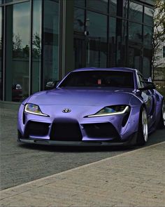 a purple sports car parked in front of a building