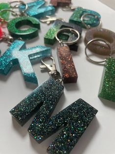 many different types of glittered key chains on a table with one being shaped like the letter k