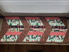 a close up of a quilted placemat on a window sill with blinds in the background