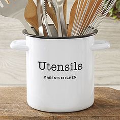 utensils are in a white pot with black lettering on the side and wooden spoons sticking out of it