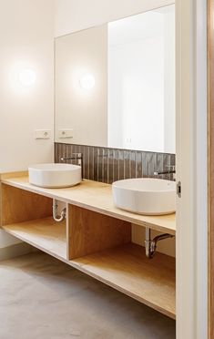 two white sinks sitting on top of a wooden shelf in a bathroom next to a mirror