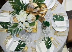 the table is set with white and gold plates, silver napkins, and flowers