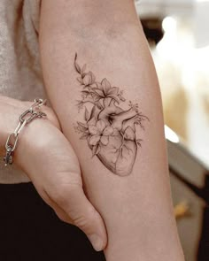 a woman's arm with a heart and flowers tattoo on it