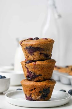 three blueberry muffins stacked on top of each other with fresh blueberries in the background