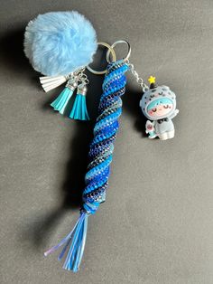 a keychain with a blue and white braided rope attached to it next to a small doll