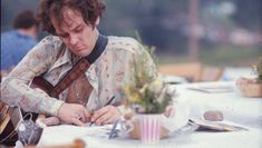 a woman sitting at a table with a guitar in her hand and writing on paper