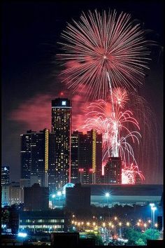 fireworks are lit up in the night sky over a cityscape and skyscrapers