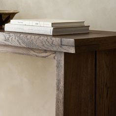 two books are sitting on top of a book shelf next to a vase and bowl