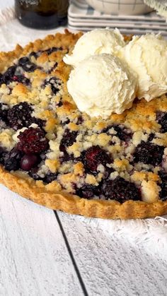 a blueberry pie with ice cream on top is sitting on a white wooden table