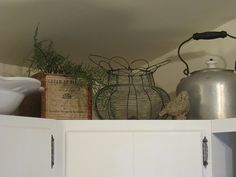 an old fashioned tea kettle is sitting on top of the cupboards