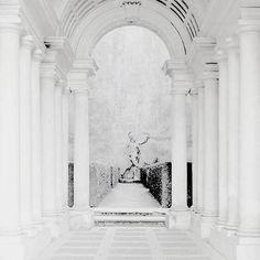 an archway with columns and a statue in the center is surrounded by white marble pillars