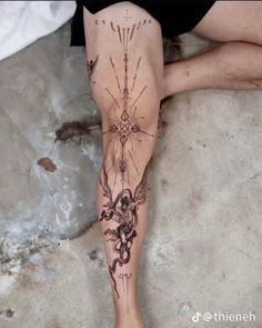 a person sitting on the ground with their legs crossed and tattoos drawn on her leg