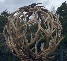 a large sculpture made out of antlers in front of trees