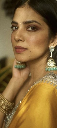 a woman in a yellow sari is posing with her hand on her chin and looking off to the side