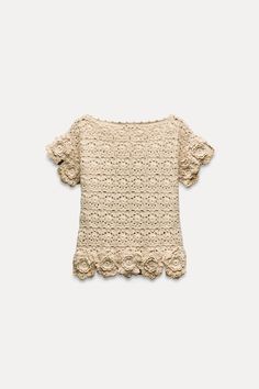 a crocheted top with ruffles on the shoulders and shoulder, in beige