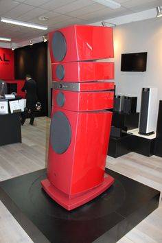 a large red speaker sitting on top of a black platform in a room filled with furniture