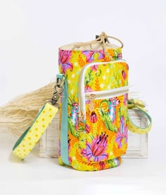 a yellow and pink flowered purse with a tag on the strap next to it