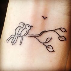 a small tattoo on the wrist of a woman with two birds perched on a branch