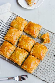 there are many pieces of pastry on the cooling rack with utensils next to it