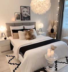 a white bedroom with black and white decor, candles and pictures on the wall above the bed