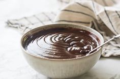 a white bowl filled with melted chocolate on top of a marble counter next to a striped towel