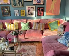 a living room filled with pink couches and pictures on the wall above them,