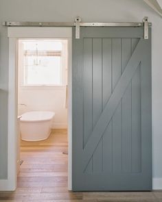 an open door leading to a bathroom with a tub and toilet in the background on a wooden floor