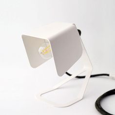 a light that is sitting on top of a white surface with a black cord attached to it