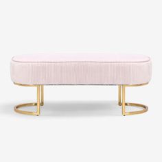 a pink bench with gold legs and a light pink upholstered cushion on it