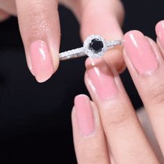 a woman's hand holding a ring with a black diamond on it and the other hand