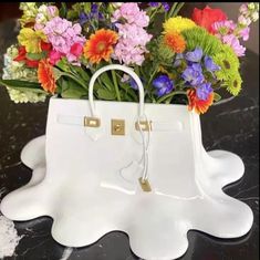 a white purse with flowers in it sitting on a table