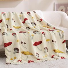 a blanket with mushrooms and mushrooms on it in front of a white couch next to a window