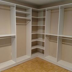 an empty walk - in closet with white shelves and wood flooring on the side