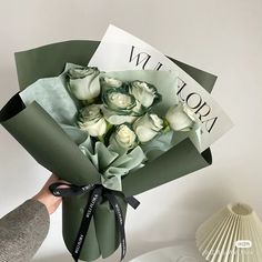 someone holding a bouquet of white roses in their hand