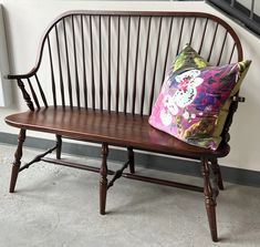 a wooden bench sitting next to a window with a pillow on it's back