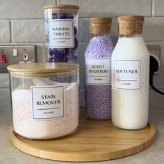 three containers with different types of bath salts on a wooden tray next to each other