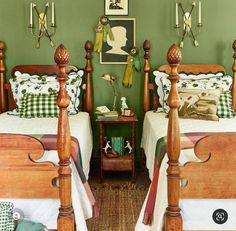 two beds in a room with green walls and wooden headboards on either side of them