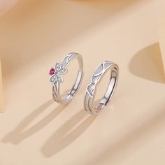 two silver rings with flowers and leaves on the top, one is pink sapphire in the middle