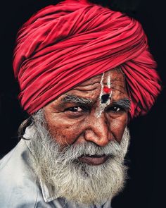 an old man with a red turban on his head