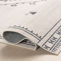 a white rug with black and grey designs on the bottom, laying on top of a wooden floor