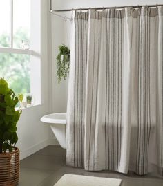 a white bath tub sitting next to a window with curtains on it's sides