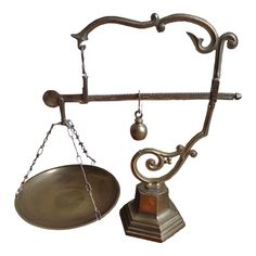 an old metal balance scale with a bowl on it's side and a chain hanging from the top